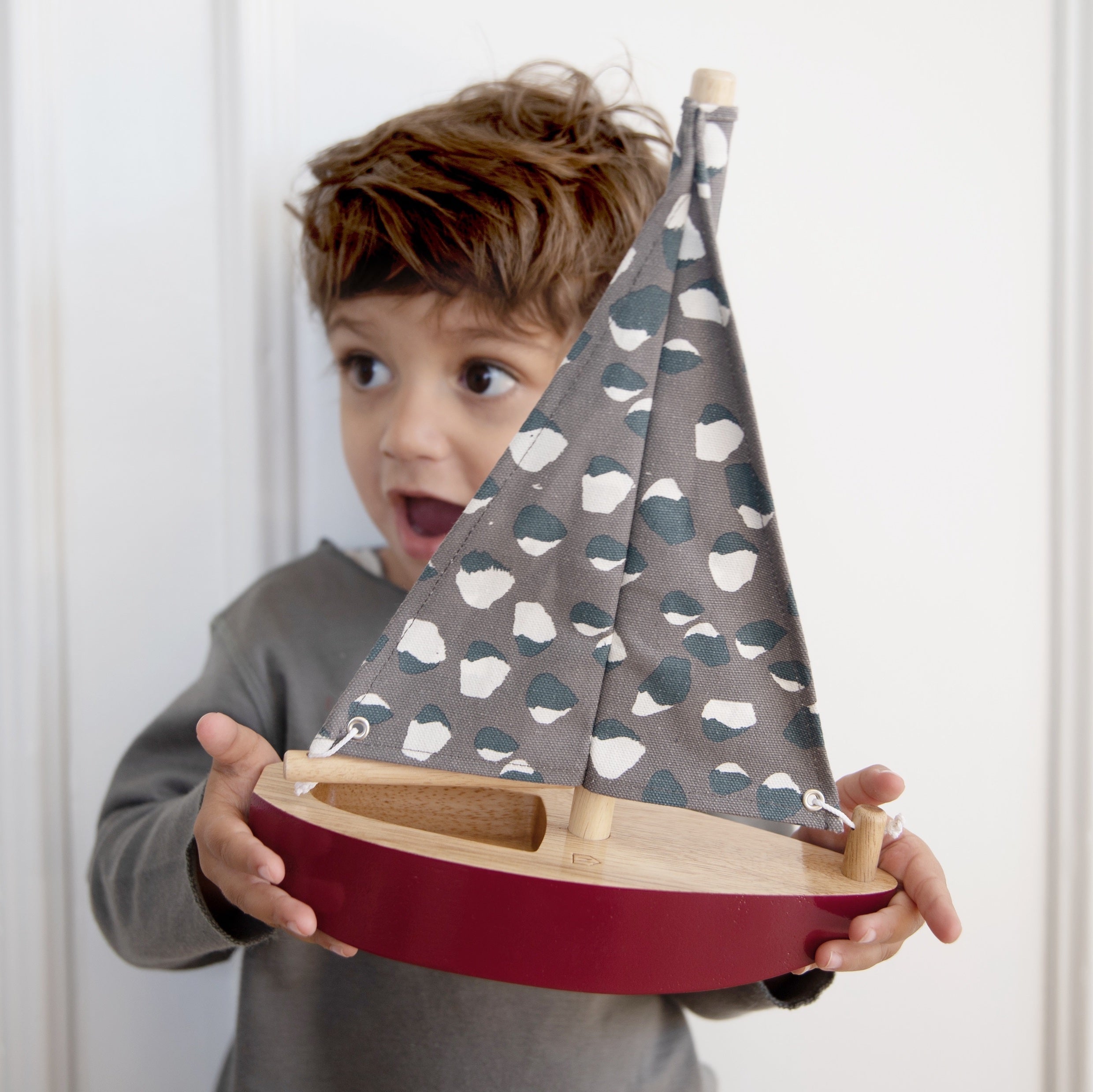 Boy holds Nofred Burgundy Toy Sailing Boat