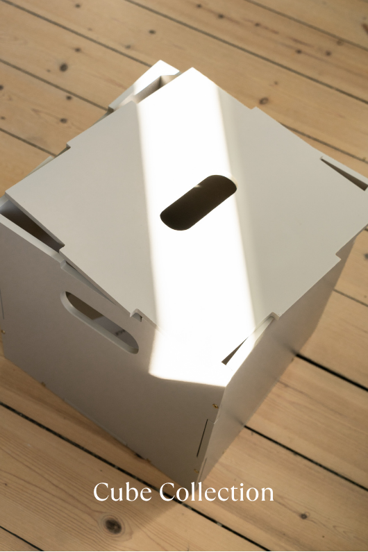White cube-shaped box on a wooden surface with 'Cube Collection' text.