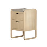 A light natural wood changing table with two drawers and a gray textured mat on top, shown against a plain white background.