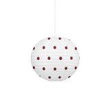 A white paper lantern pendant light with dark red polka dots, suspended by a thin white cord against a solid white background.