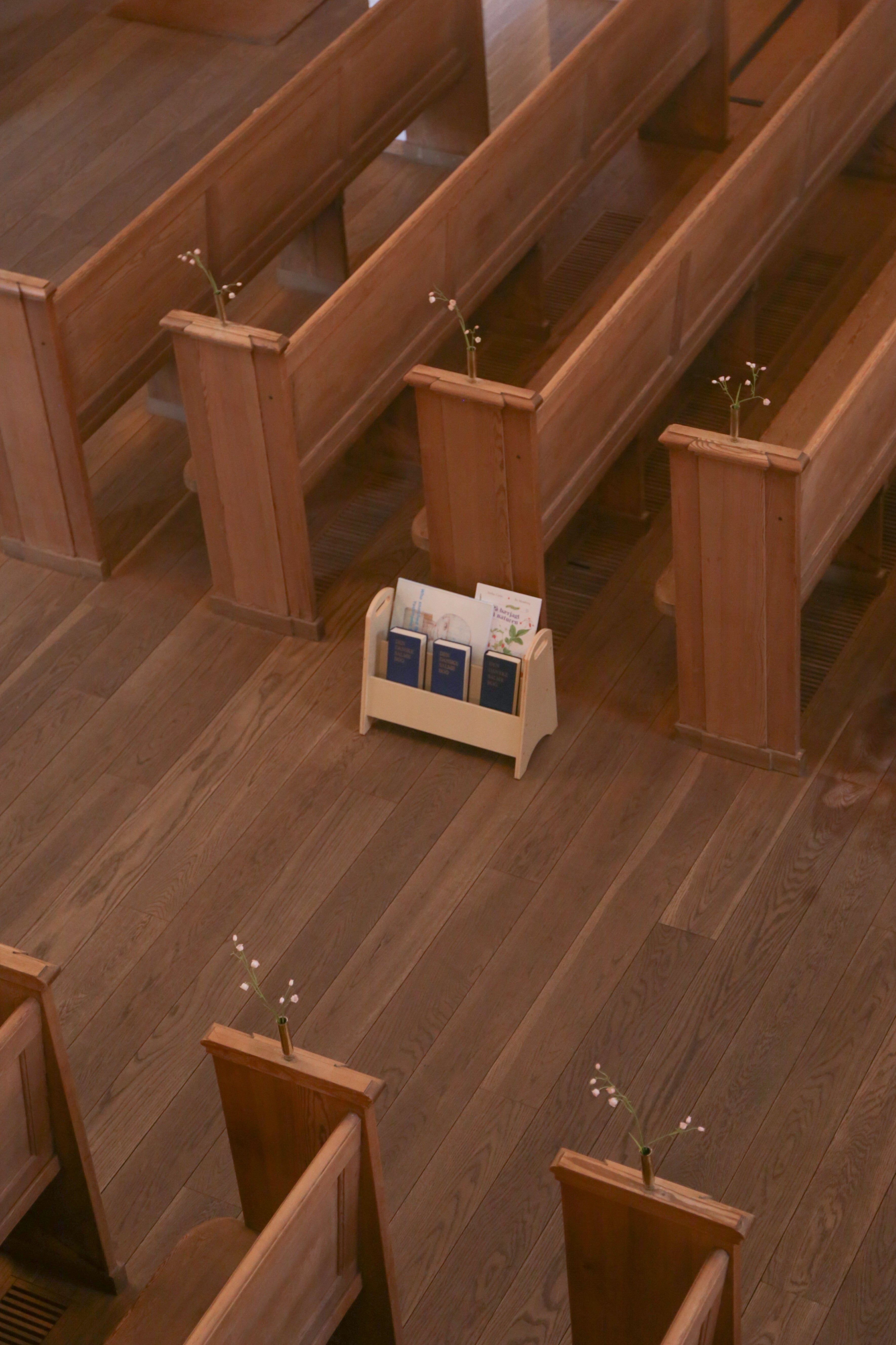 Wooden pews in a church with a magazine rack in the center.