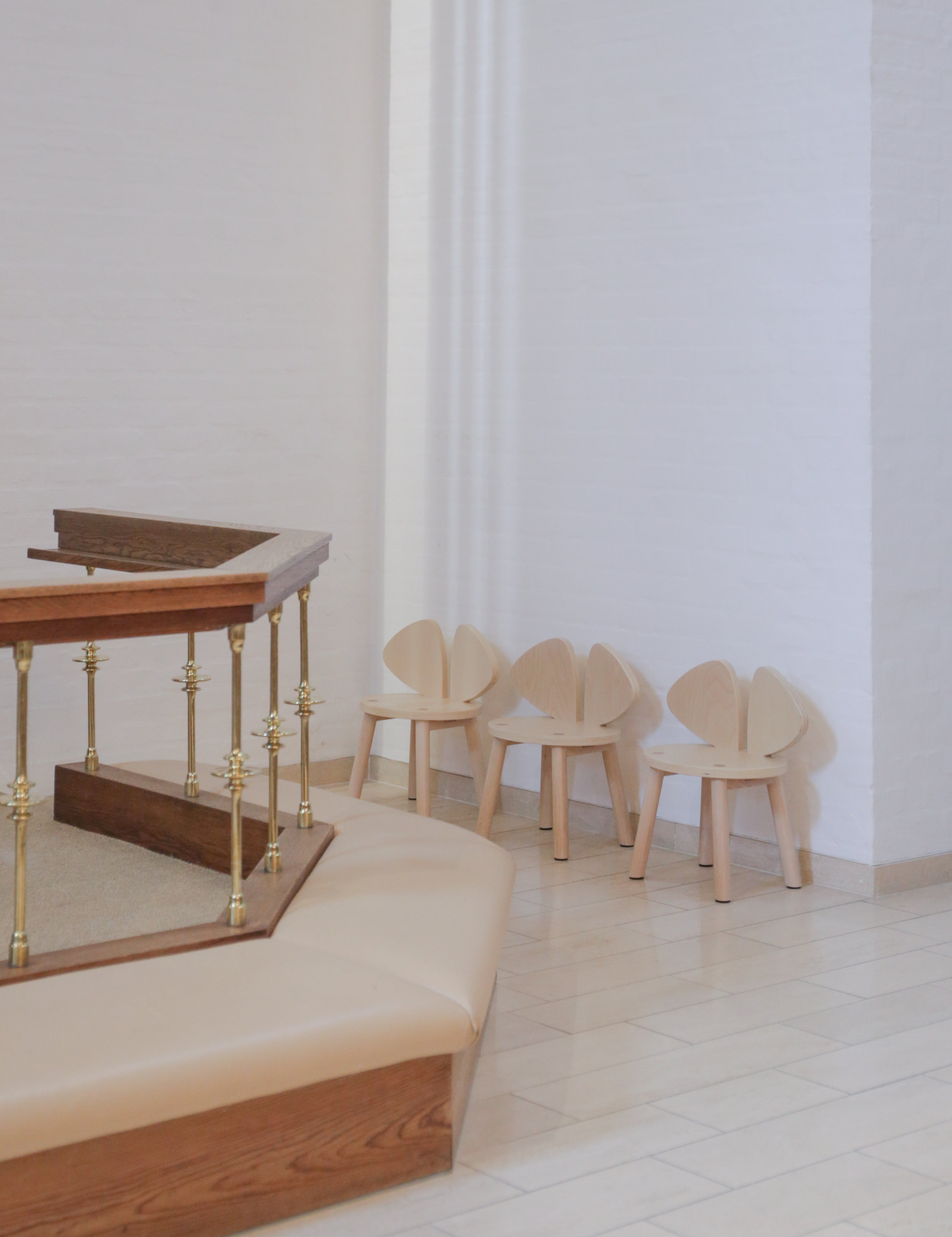 Wooden chairs and table in a minimalistic room with white walls and floor.