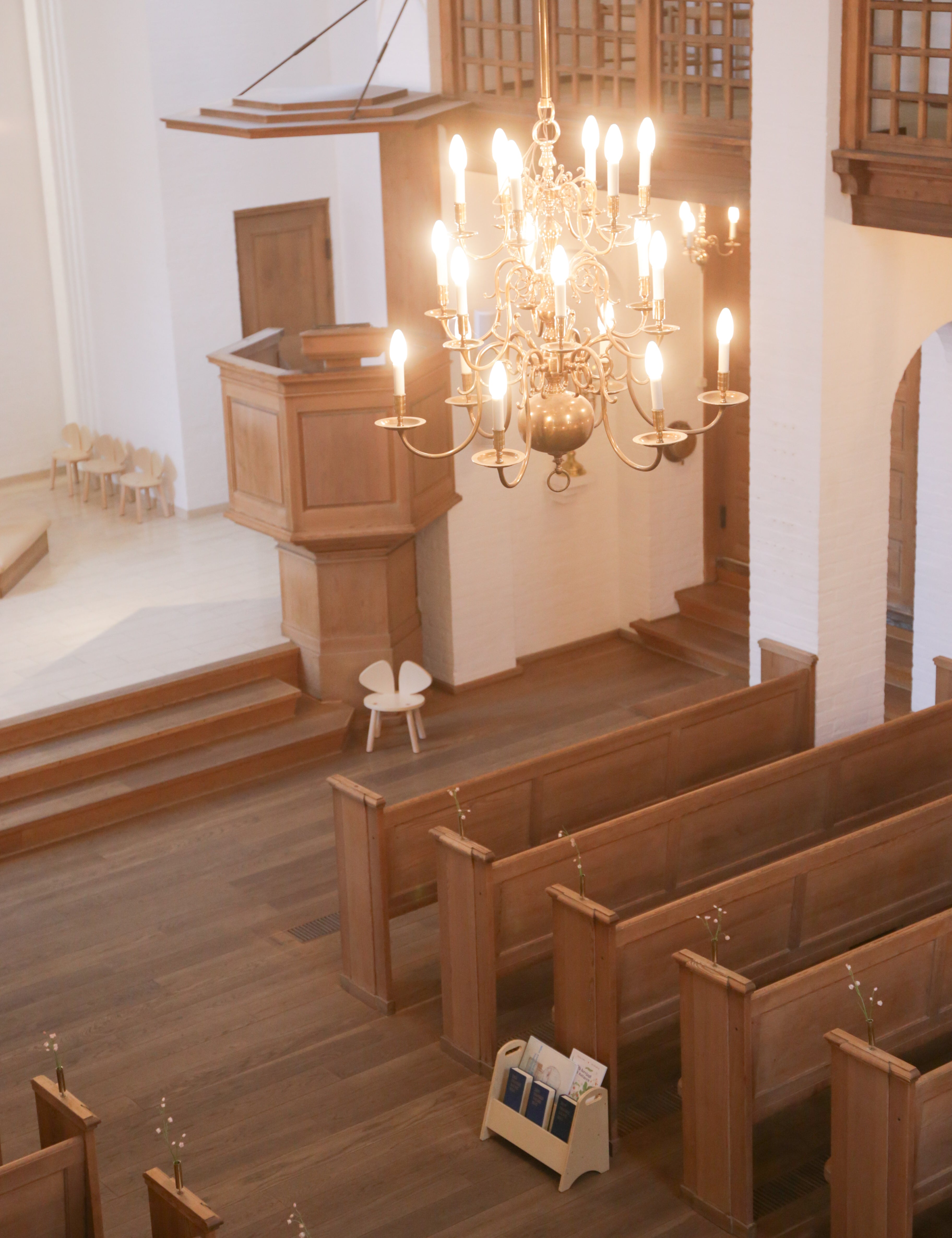 Interior of a church with wooden pews, pulpit, and chandelier.