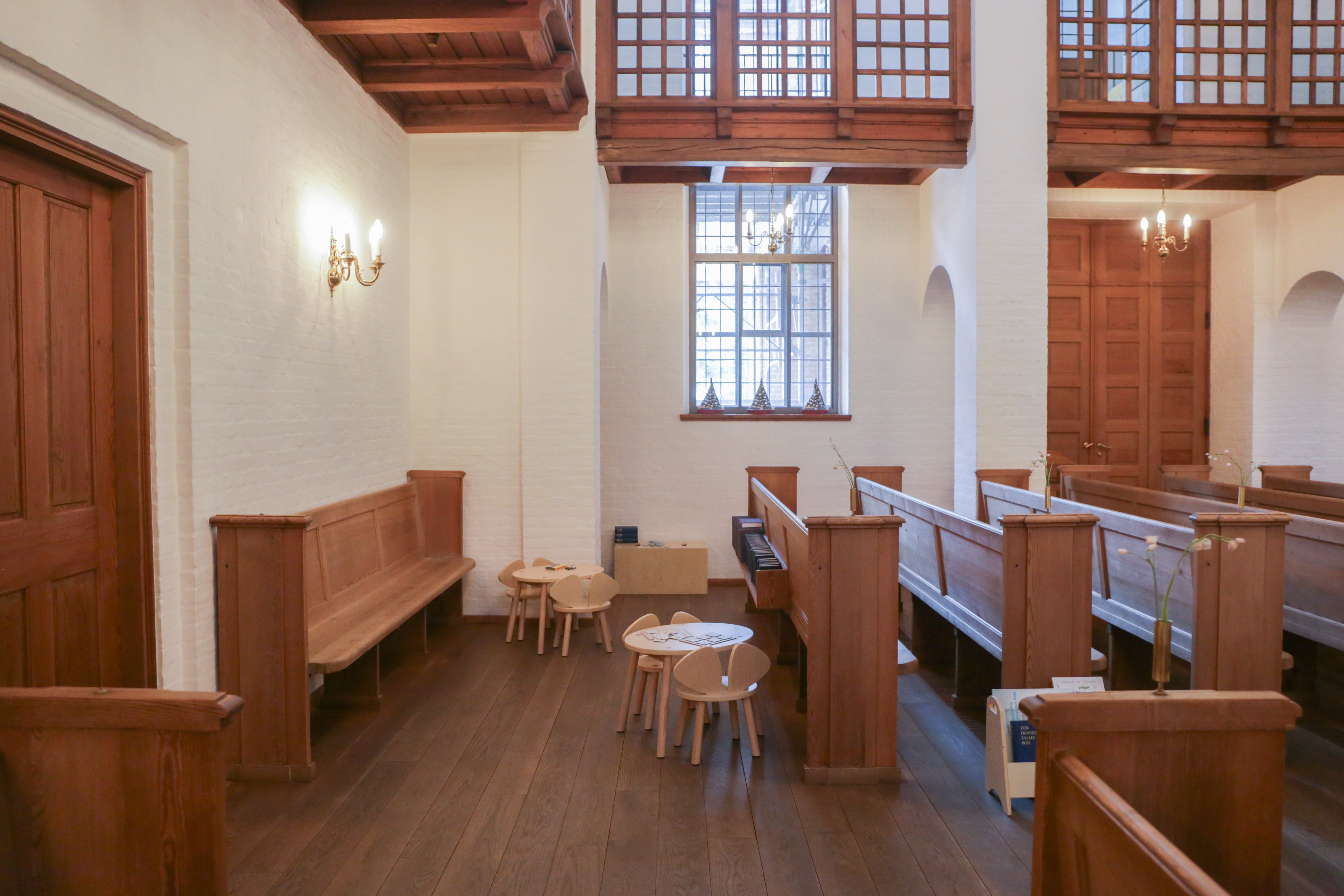 Narrow church interior with wooden pews and a small table.