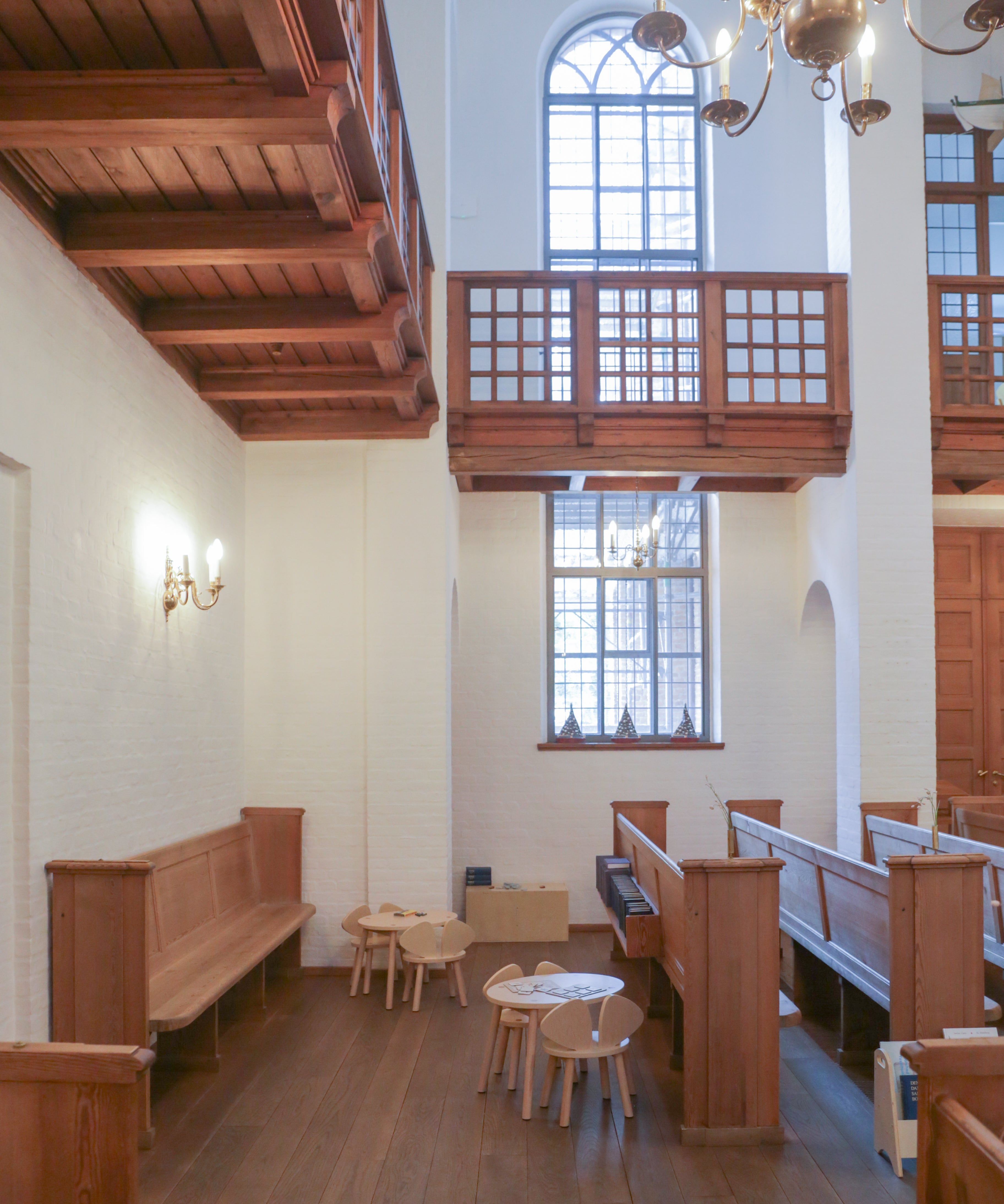Interior of a church with wooden pews, tables, and chairs, high ceiling with wooden beams.