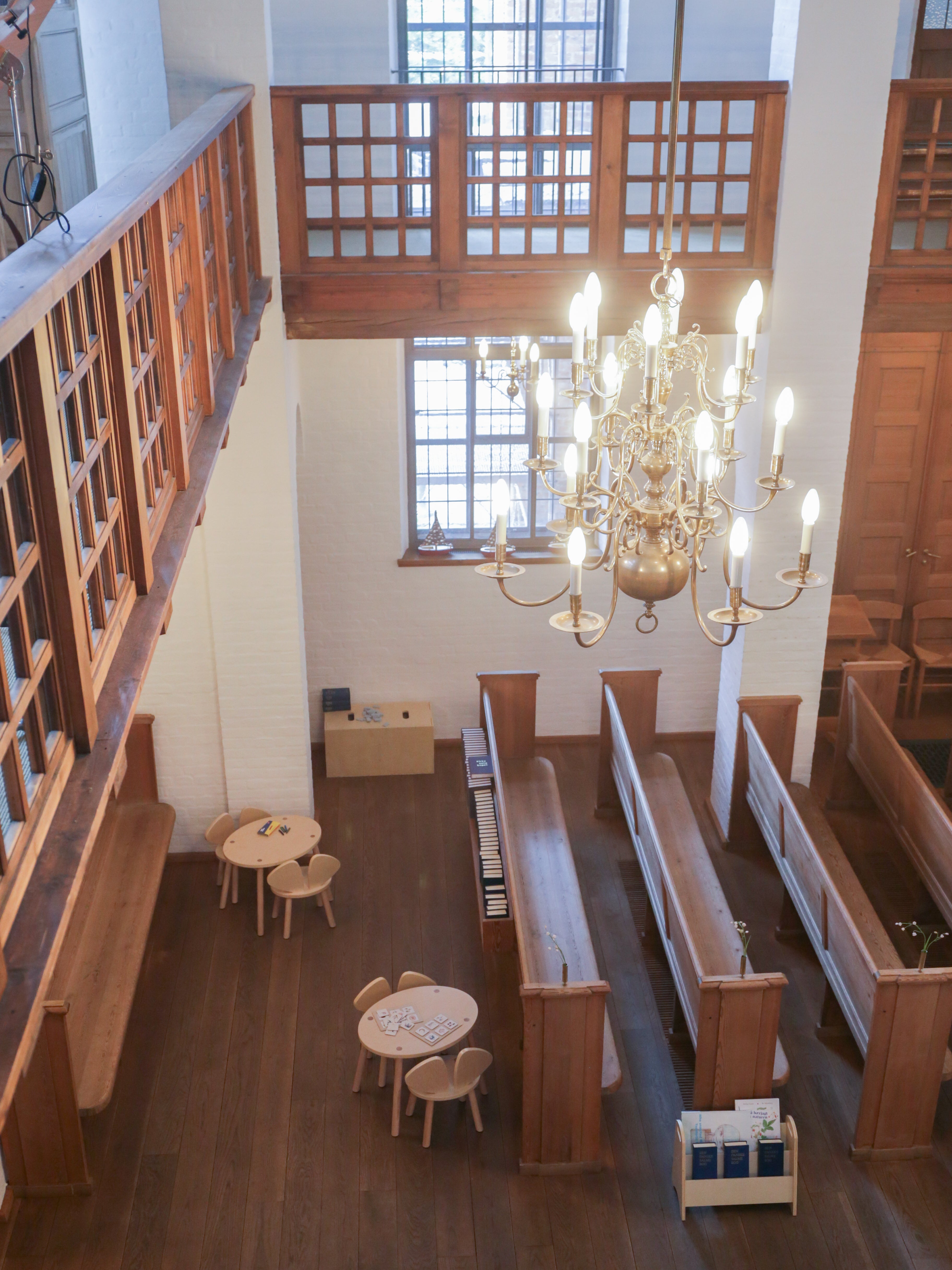 Interior of a church with wooden pews, tables, and a chandelier.