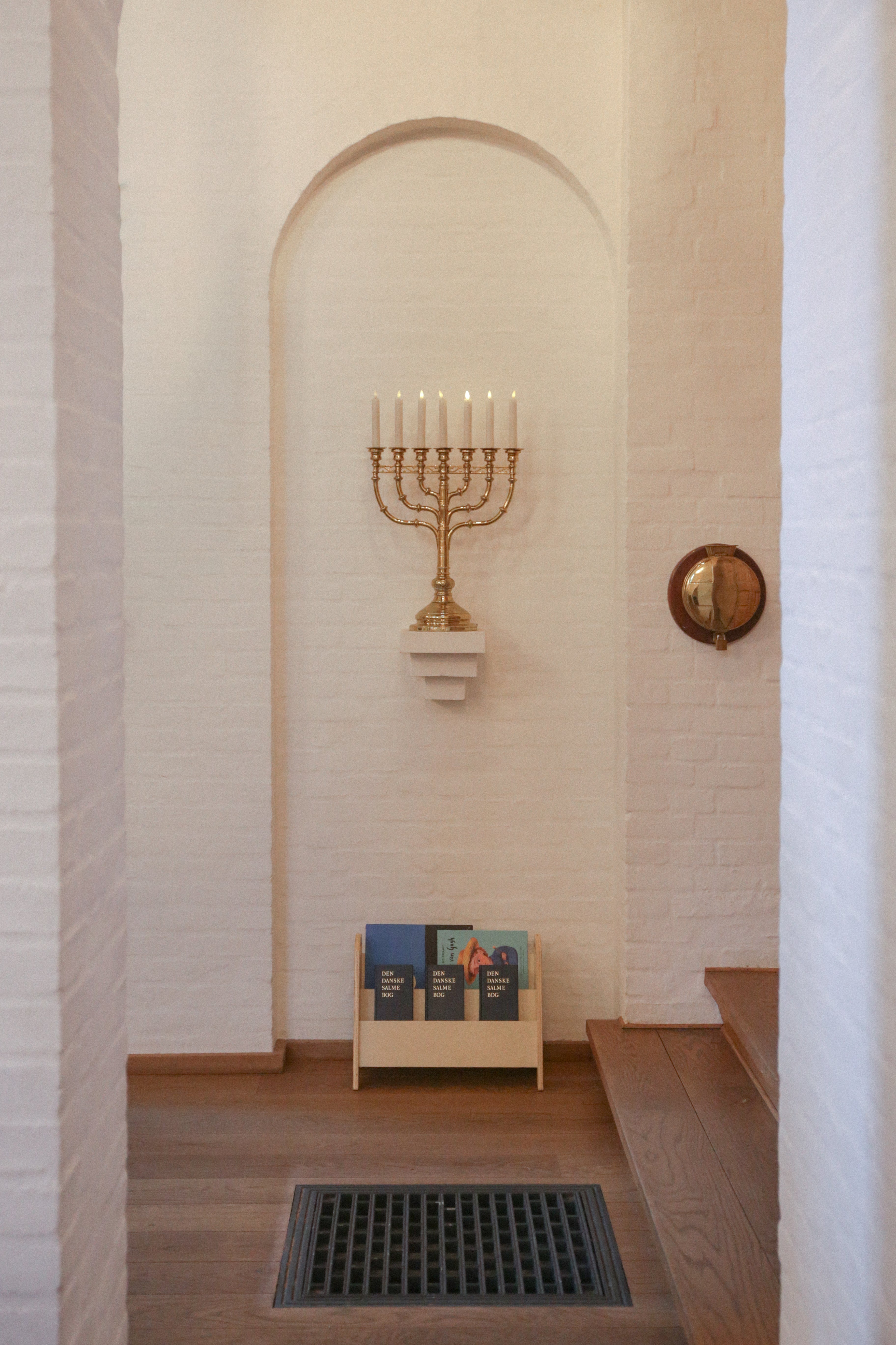 Narrow hallway with a Menorah on a white brick wall