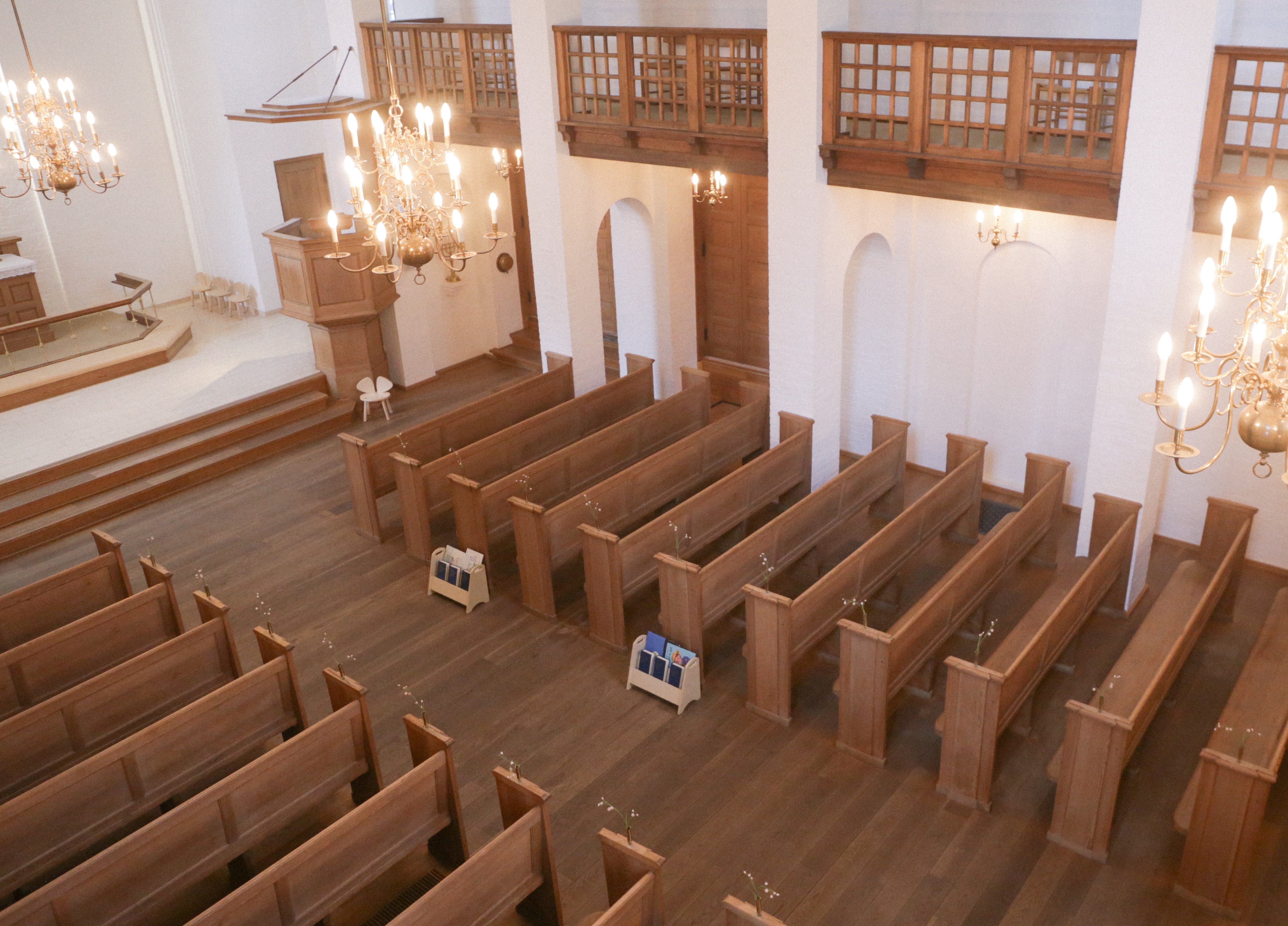 Empty church interior with wooden pews and chandeliers.