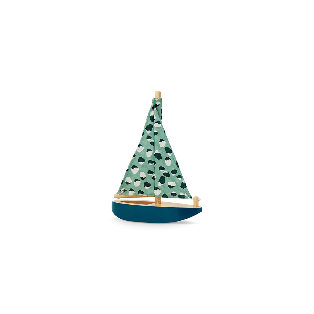 A small wooden toy sailboat with a dark green patterned sail, teal and white motifs, and a deep blue hull, shown on a plain white background.