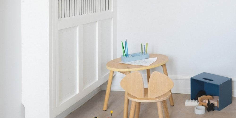 Children's wooden table and chairs with toys in a room setting.