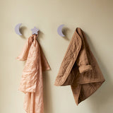 Scarf and kids jacket hanging on hooks in purple