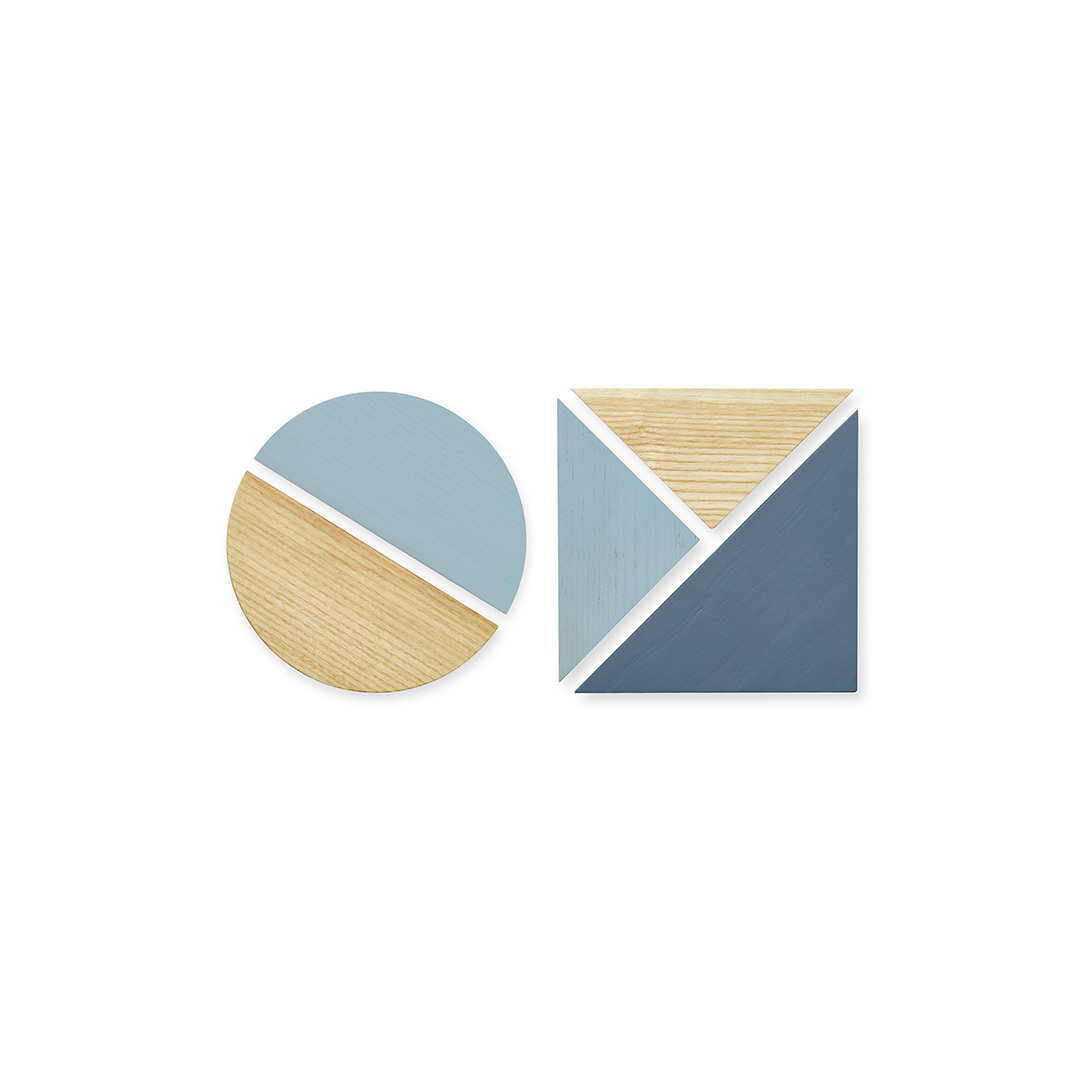 Two modern geometric coasters on a plain white background. One coaster is circular, and the other is square, both featuring a color-blocked design with light blue, slate blue, and natural wood grain sections separated by white borders.