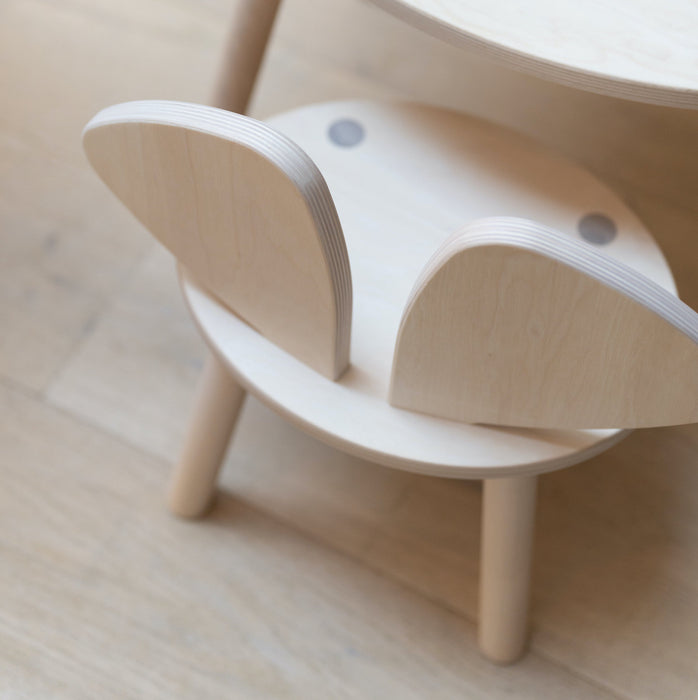 Mouse chair i birch standing next to the table 