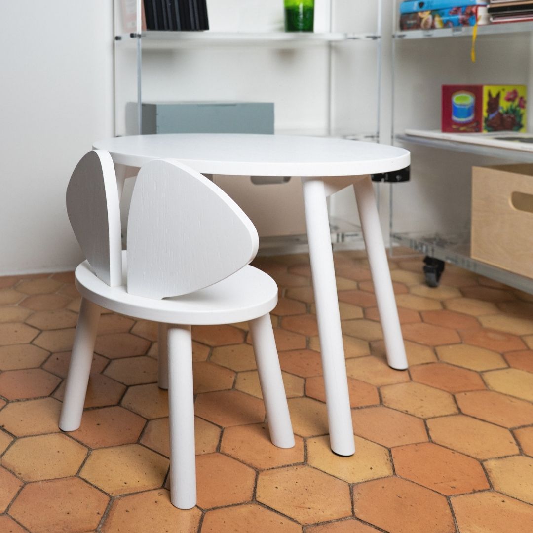 White children's table and chair set on a hexagonal tiled floor.