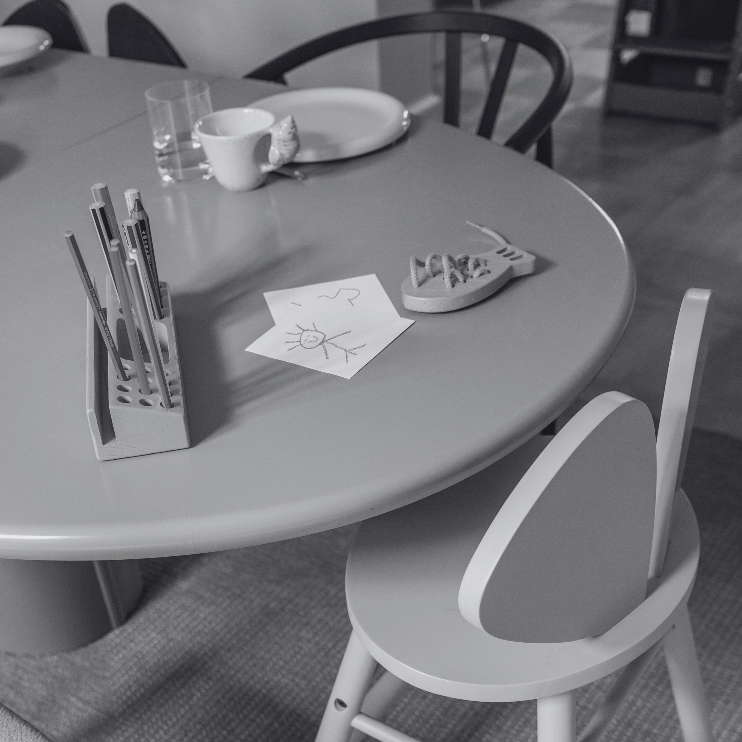 Round table with stationery items and a chair in a room setting