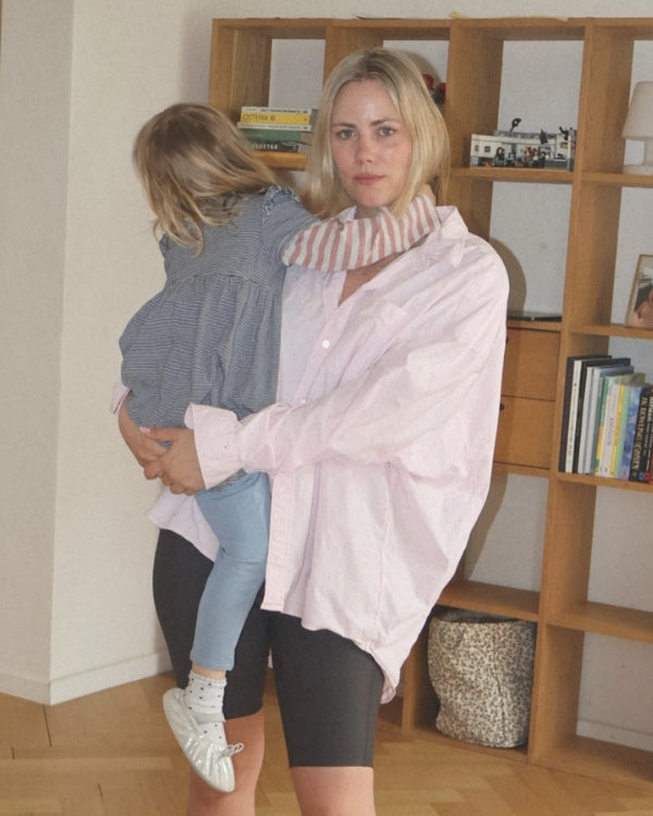 Woman holding a child in a room with wooden bookshelves.