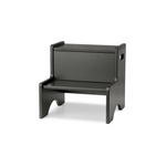 A minimalist black step stool with a rectangular backrest and integrated armrests, shown from a three-quarter angle on a white background.