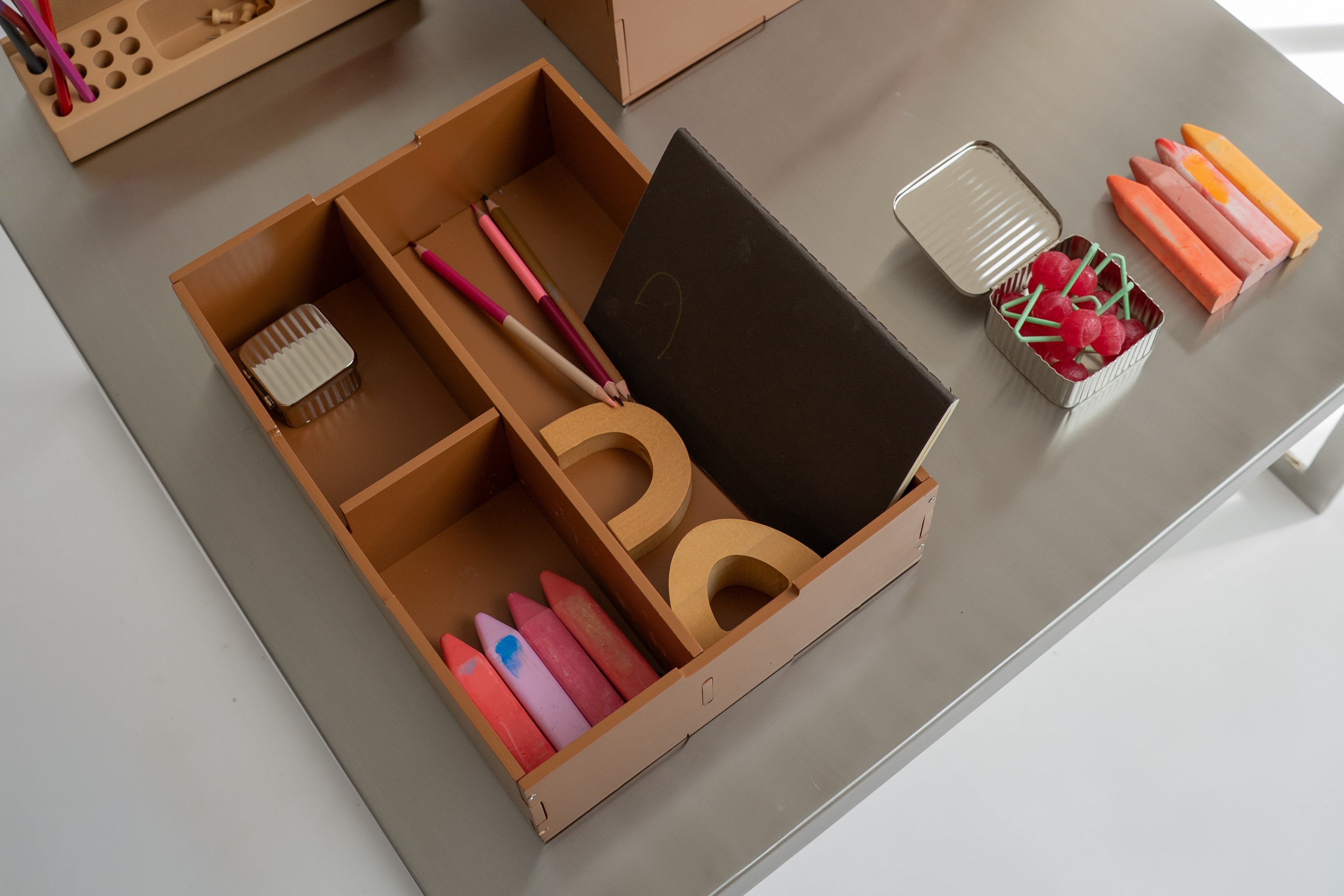 Collection of wooden toys and storage boxes on a light gray surface.