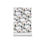 A roll of wallpaper with a repeating pattern of black toucans, green ferns, and branches on a white background, shown partially unrolled against a plain white backdrop.