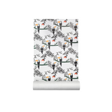 A roll of wallpaper with a repeating pattern of black toucans, green ferns, and branches on a white background, shown partially unrolled against a plain white backdrop.