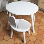 White children's table and chair set on a hexagonal tiled floor.