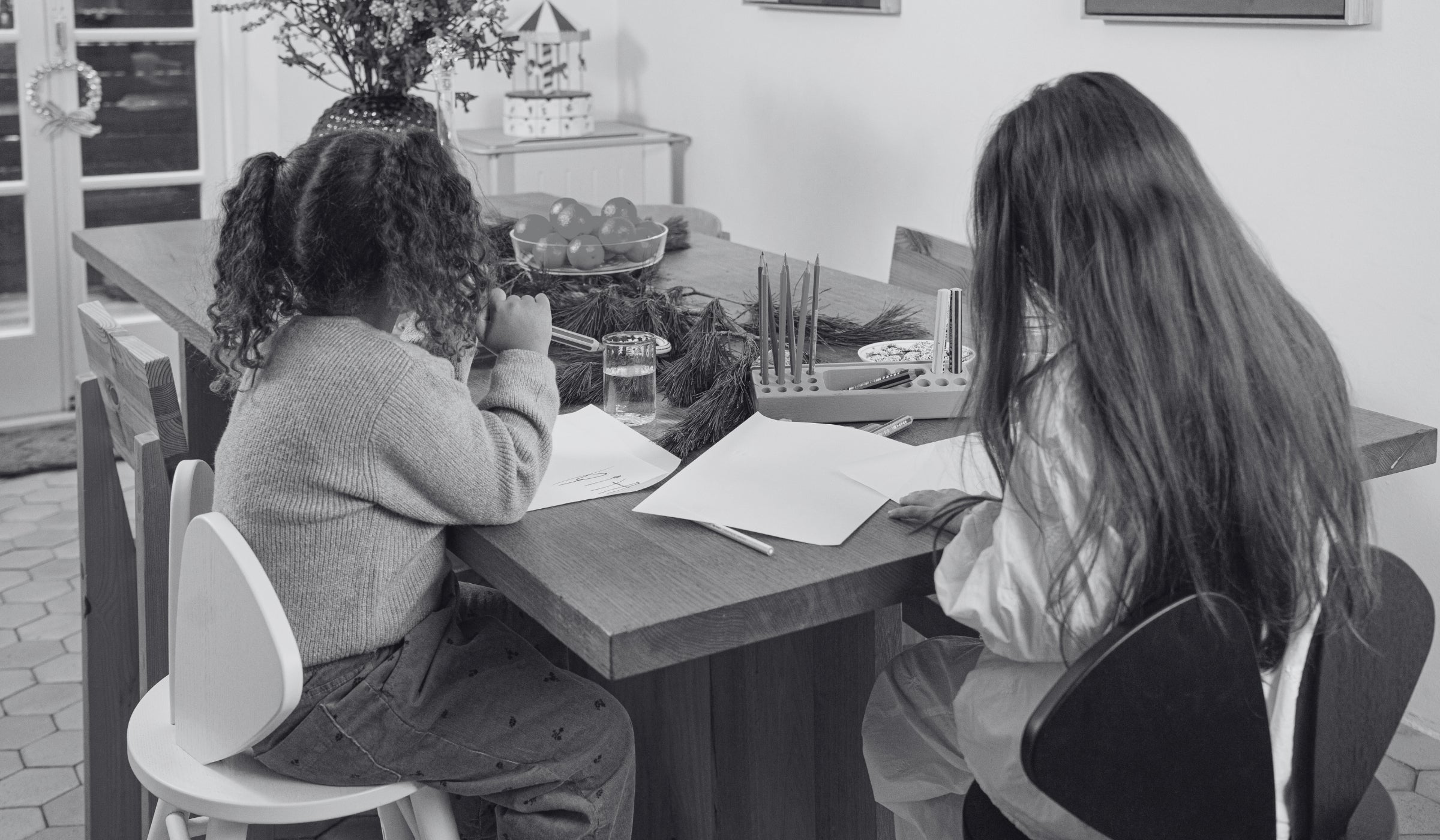 Two people sitting at a table with books and stationery in a classroom setting.
