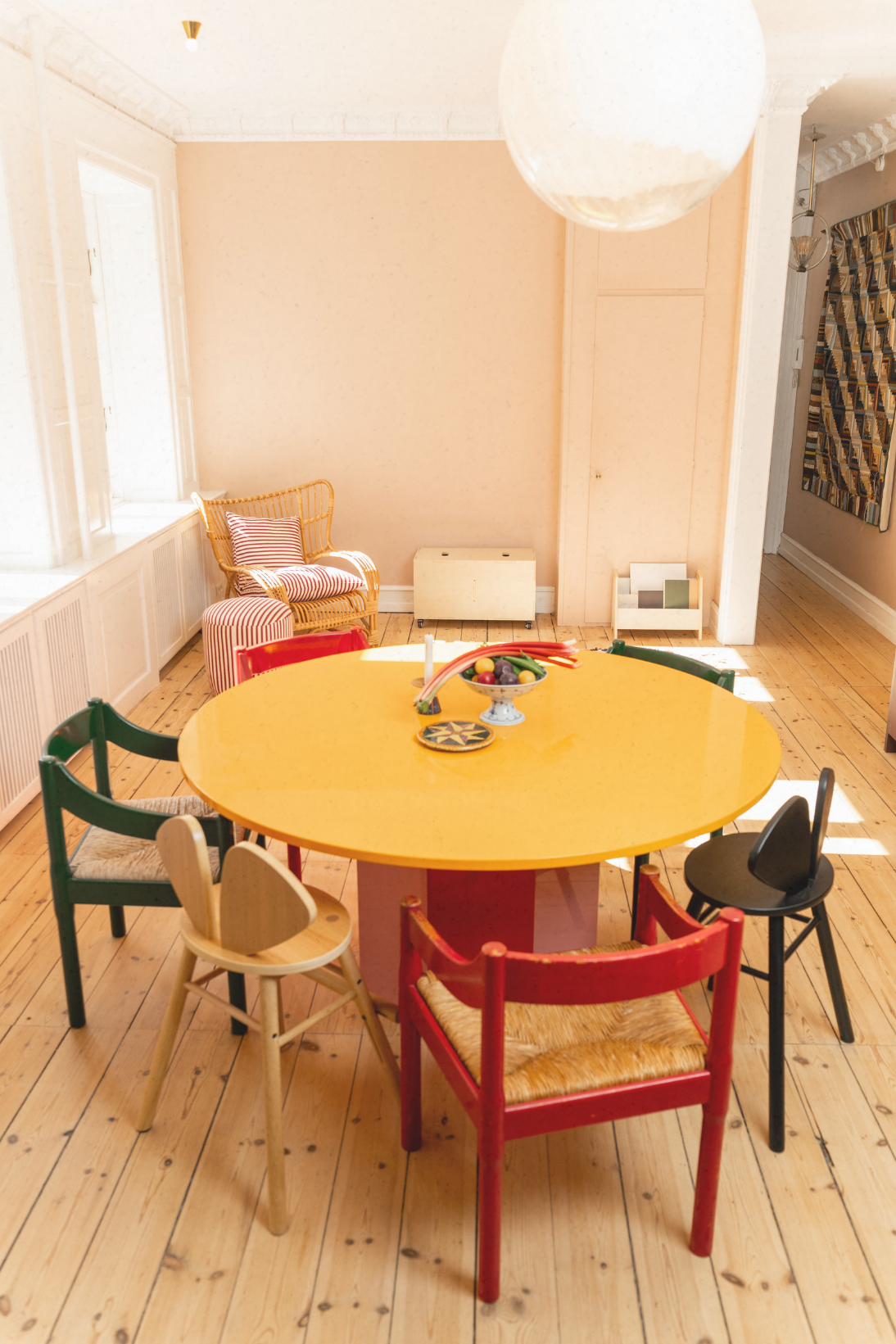 Colorful round table with chairs in a room with wooden floors and white walls.
