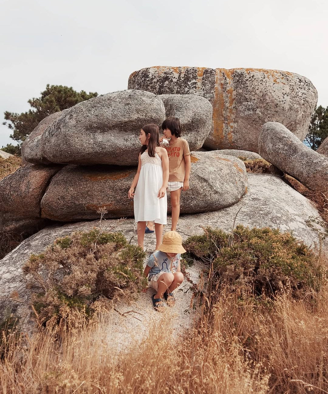 Three women standing on large rocks with a natural landscape background