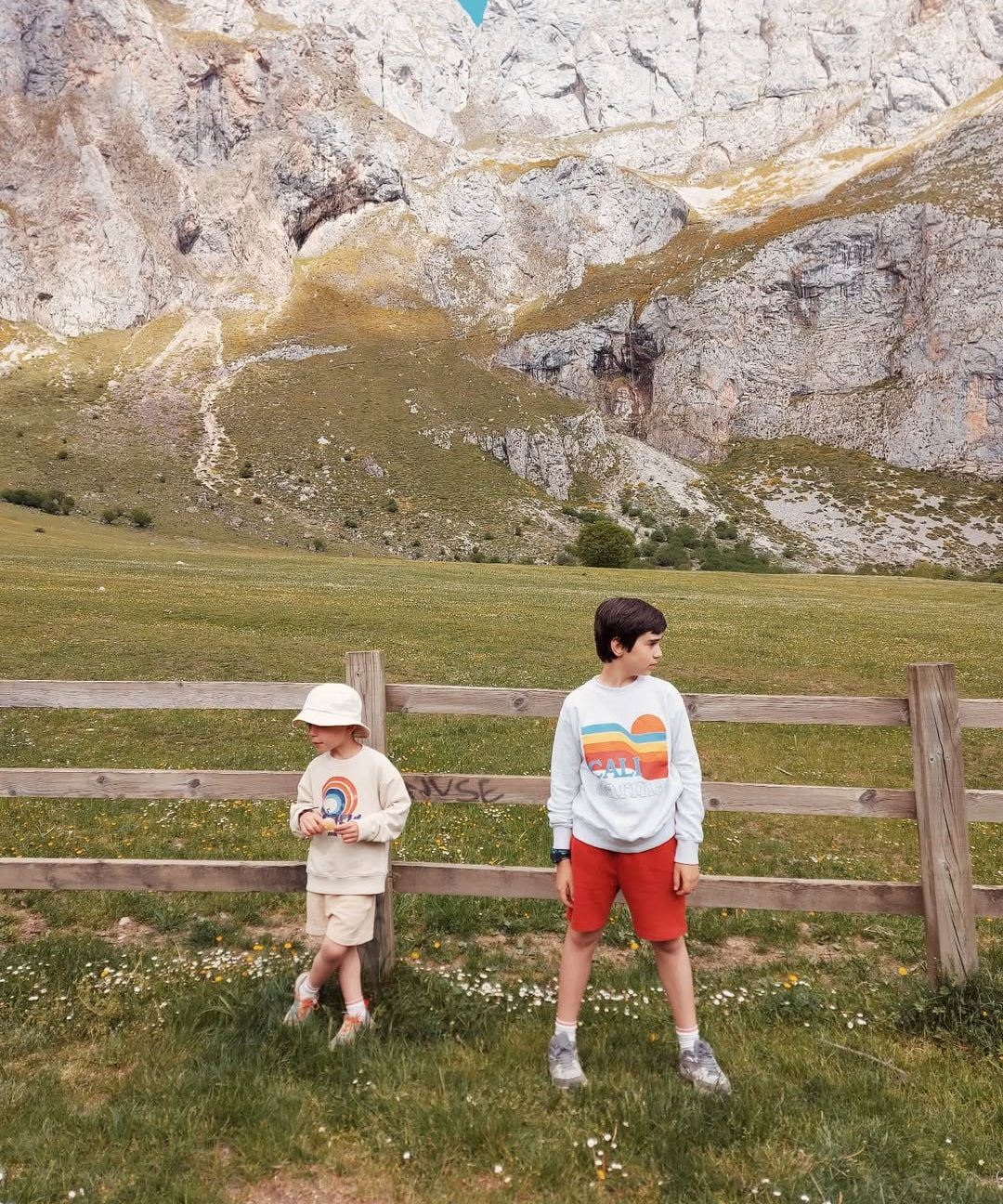 Two children standing in a field with mountains in the background
