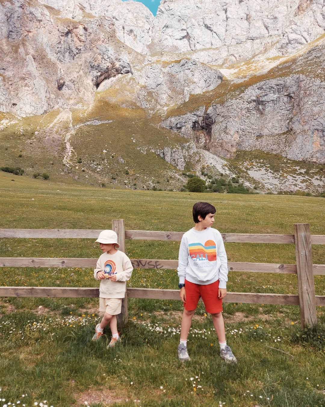 Two children standing in a field with mountains in the background