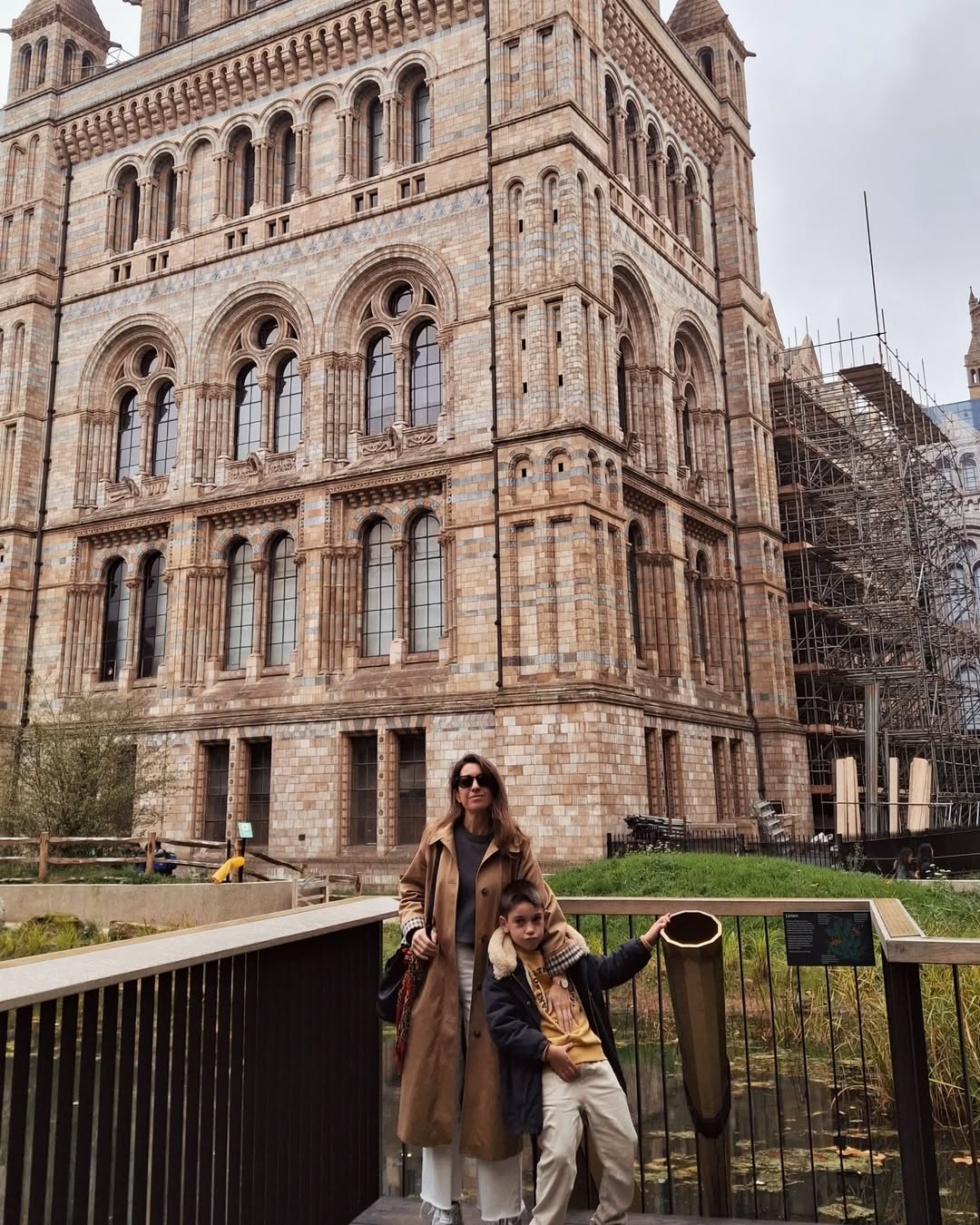 Two people standing in front of a large stone building with architectural details.