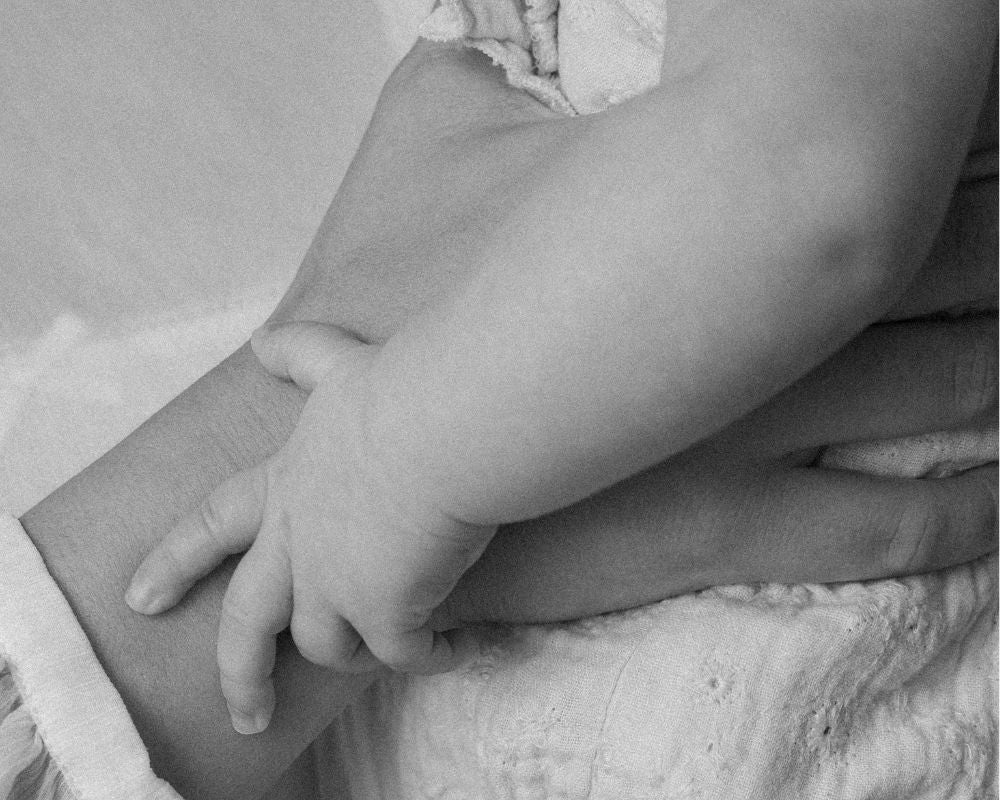 Close-up of a baby's legs and feet wrapped in white fabric on a light background