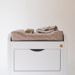 White dresser with folded clothes on a plain background