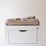White dresser with folded clothes on a plain background