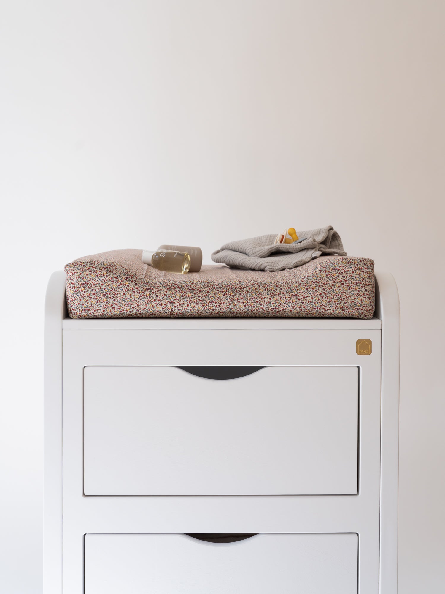 White dresser with folded clothes on a plain background