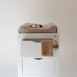 White changing table with brown towels on a plain white background