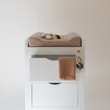 White changing table with brown towels on a plain white background