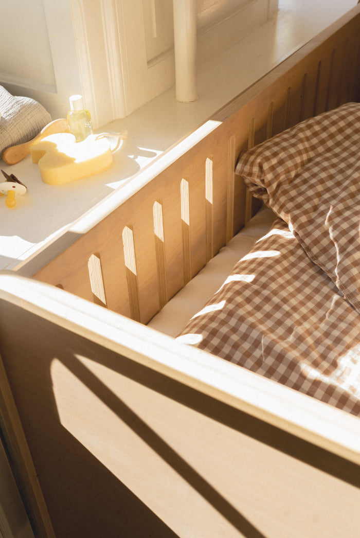 Wooden crib with checkered blanket and toys in a softly lit room