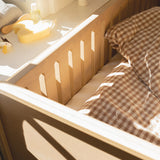 Wooden crib with checkered blanket and toys in a softly lit room