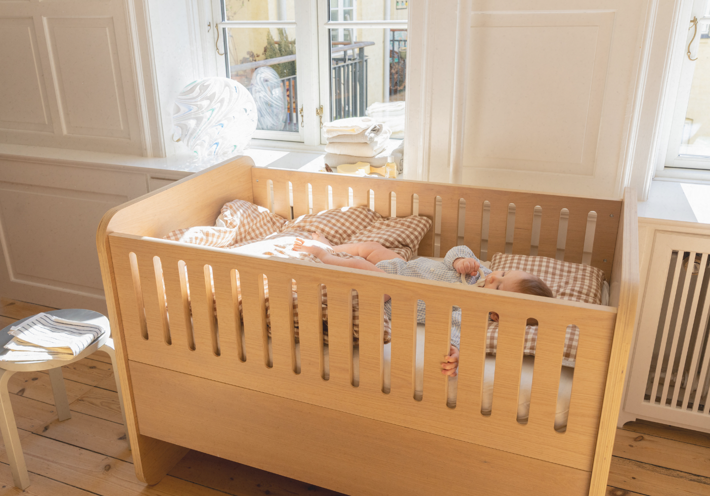 Wooden crib with baby inside in a bright room
