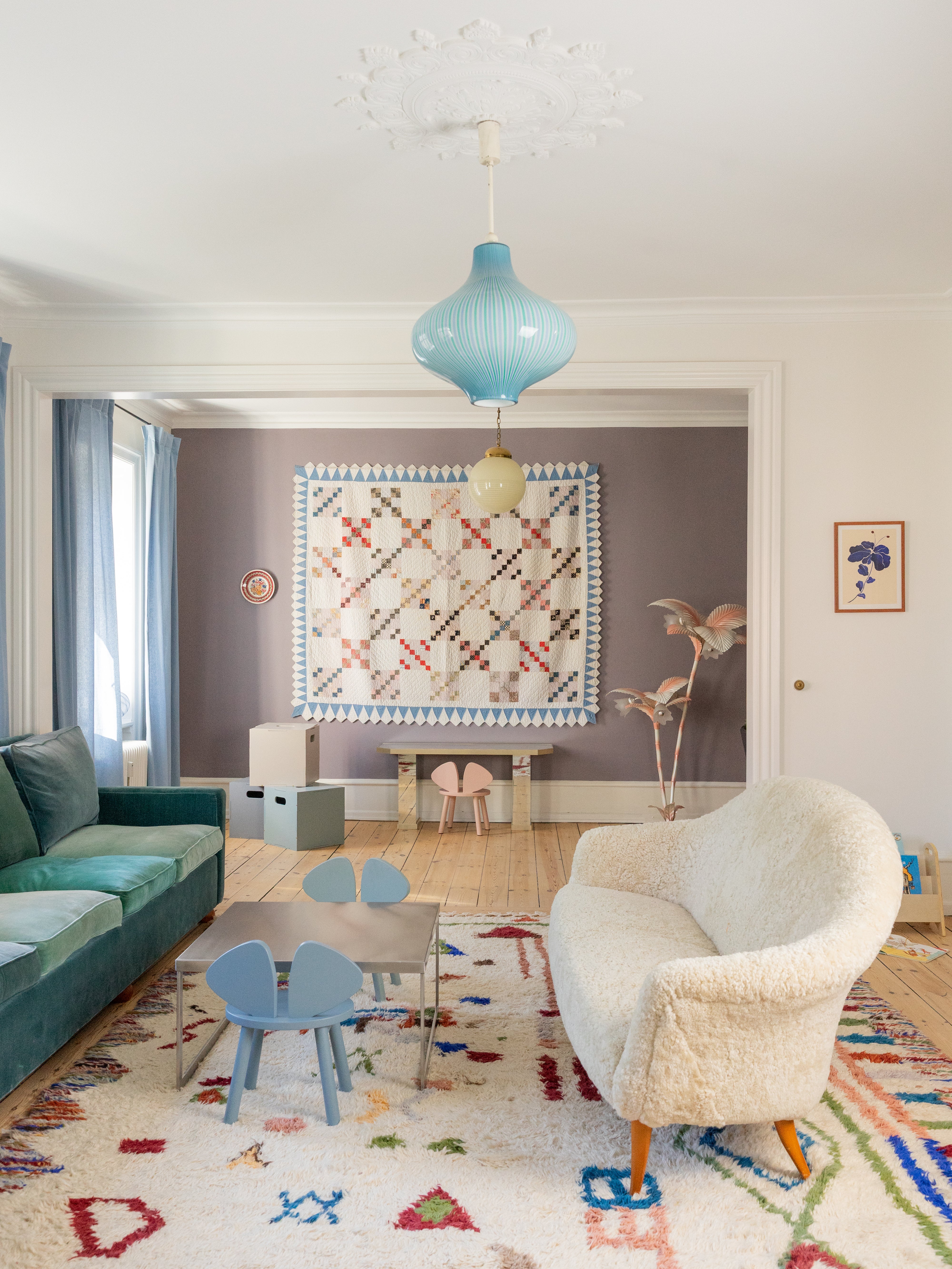Modern living room with a colorful rug, blue sofa, and white armchair.
