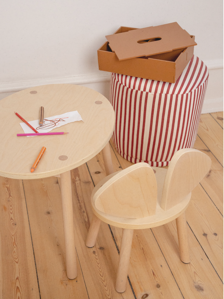 Children's wooden table and chair set with art supplies on a wooden floor.
