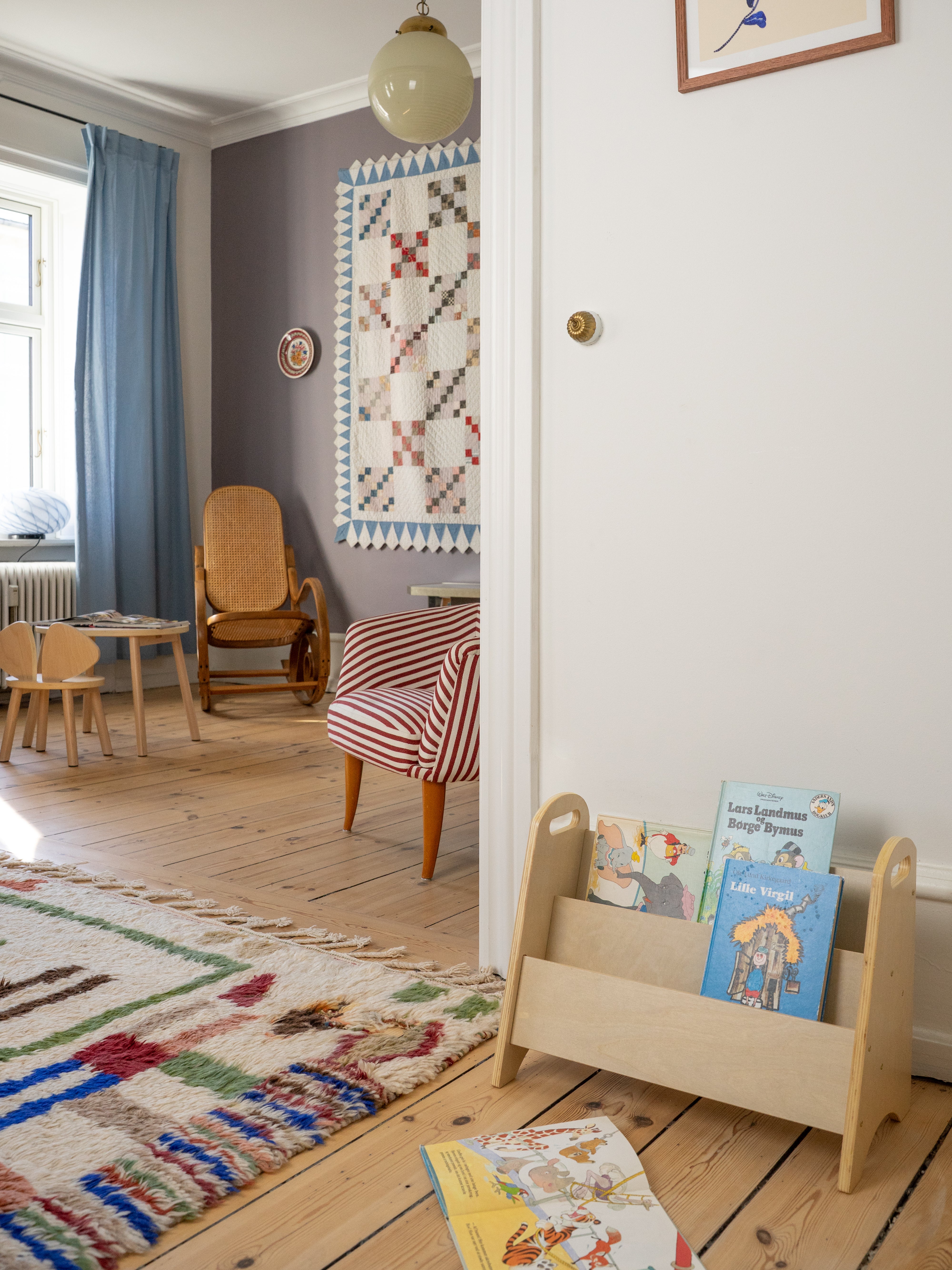 Children's room with wooden bookshelf, colorful rug, and chairs.