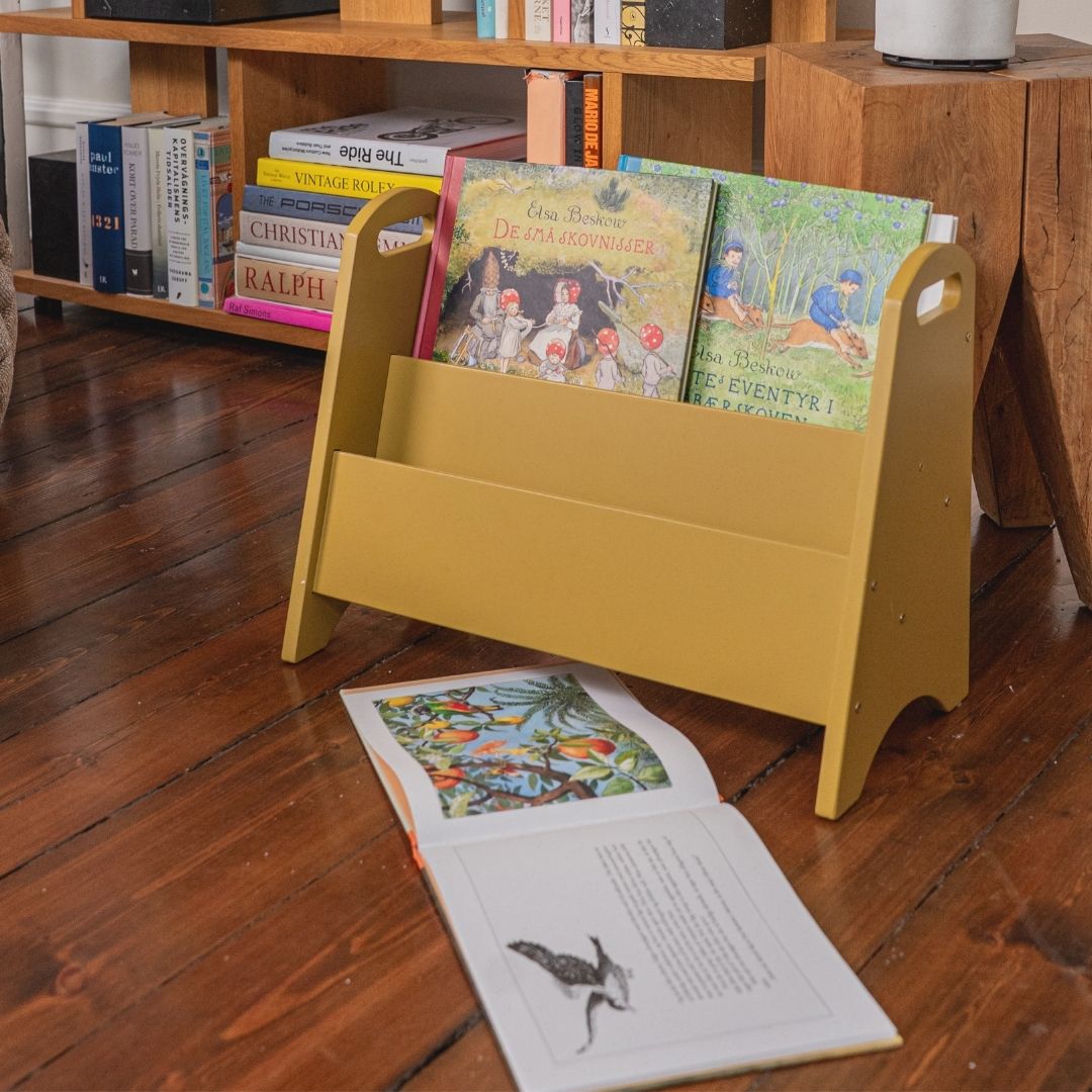 Yellow bookshelf with children's books on a wooden floor