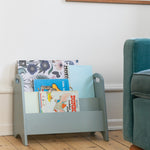 Children's bookshelf with books in a room with a blue armchair.