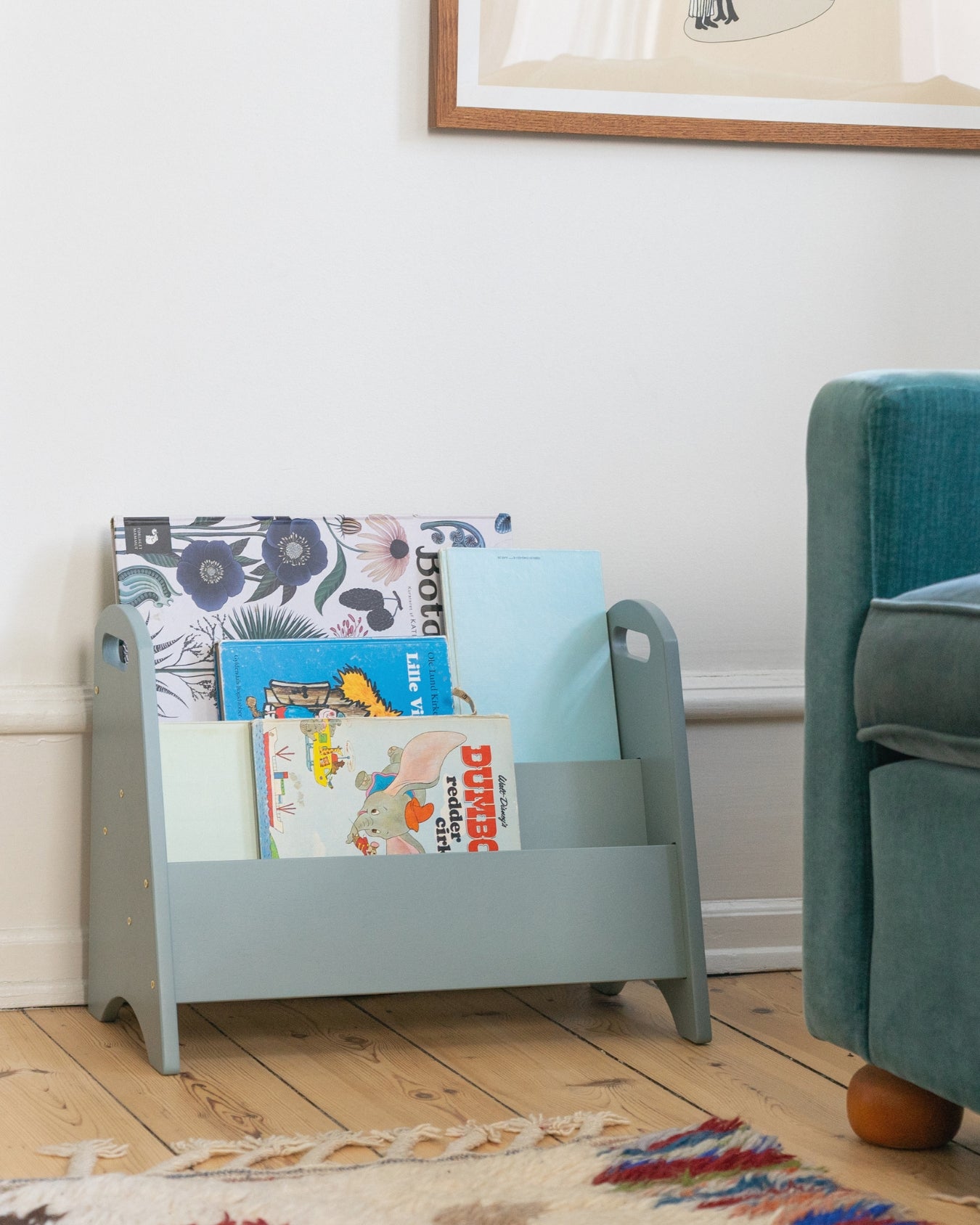 Children's bookshelf with books in a room with a blue armchair.