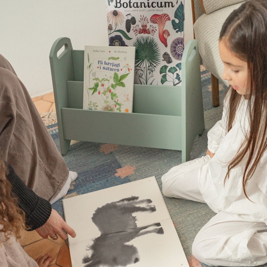 Two children sitting on the floor with a book and a picture of a horse.