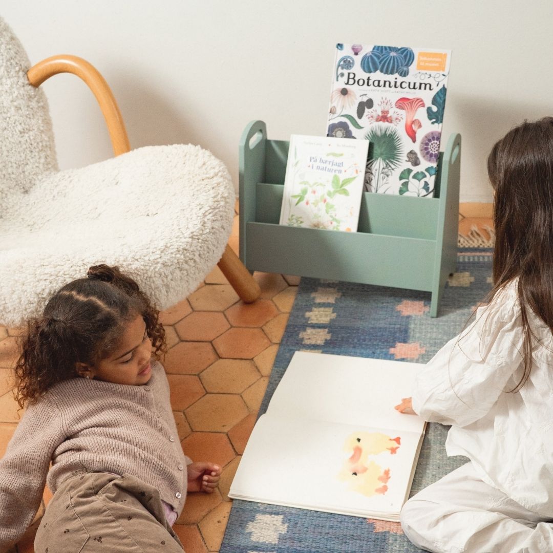 Two children sitting on a rug reading books in a cozy room.