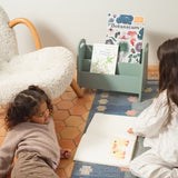 Two children sitting on a rug reading books in a cozy room.
