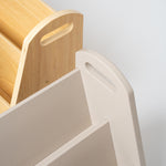 Close-up detail of a modern storage unit or bookshelf, showing a light beige plastic tiered section with a handle cutout next to a natural wood slatted section on a light gray background.